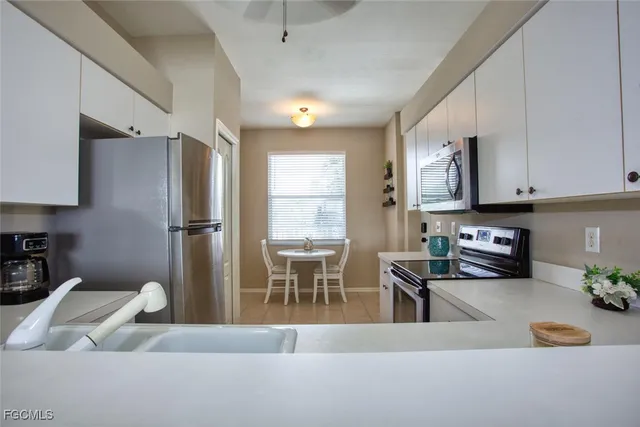 a kitchen with stainless steel appliances granite countertop a refrigerator a sink a stove and white cabinets