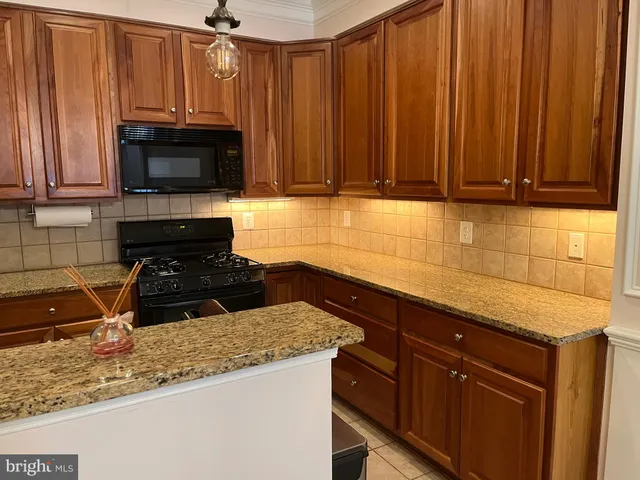 a kitchen with granite countertop wooden cabinets and a stove top oven
