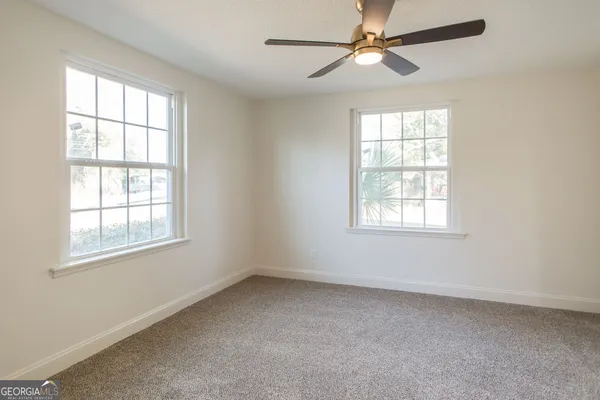 an empty room with a window and a fan