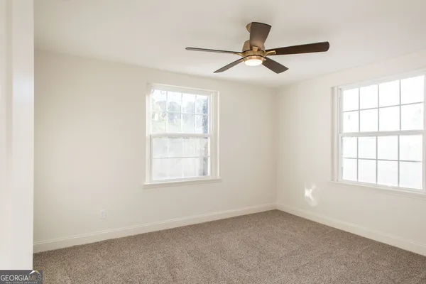 an empty room with windows and fan