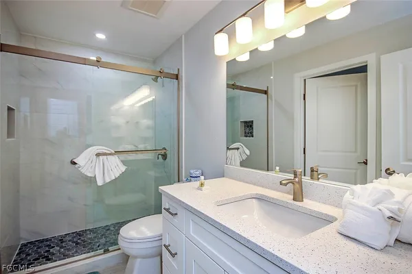 a bathroom with a granite countertop sink a mirror a toilet and shower