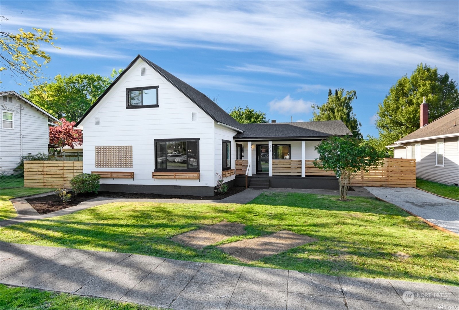 a view of a yard in front of a house with plants and large tree