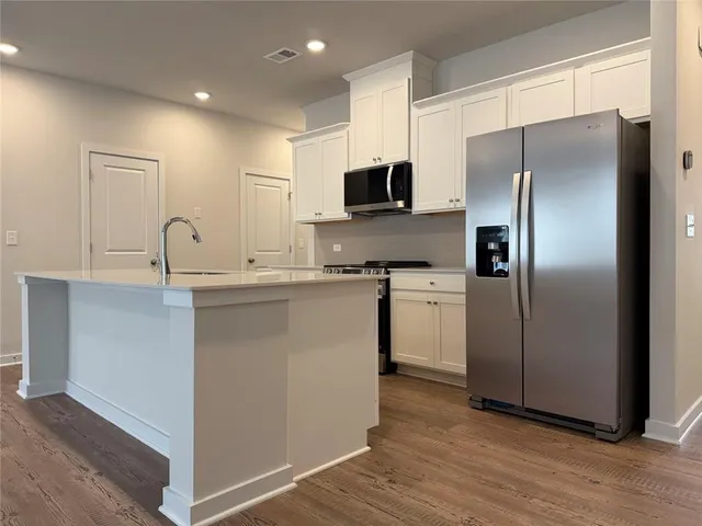 a kitchen with kitchen island a counter top space cabinets and stainless steel appliances