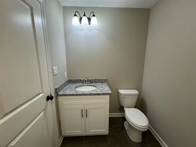 a bathroom with a granite countertop toilet and a sink