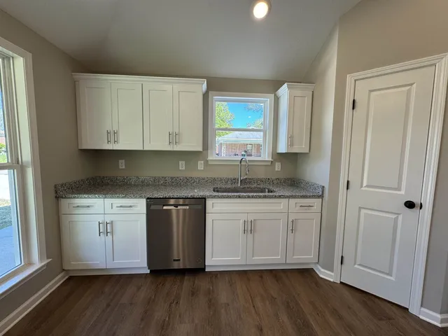 a kitchen with granite countertop white cabinets and white appliances