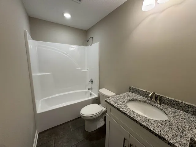 a bathroom with a granite countertop sink a toilet and shower