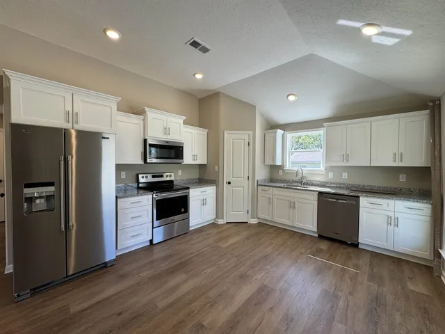 a kitchen with granite countertop a refrigerator and a stove top oven