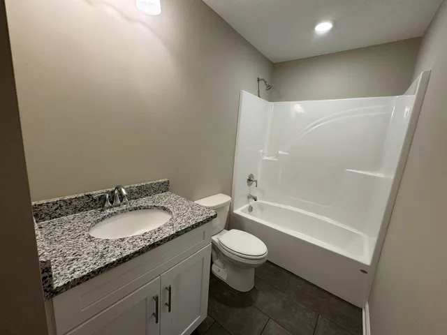 a bathroom with a granite countertop sink a toilet and bathtub