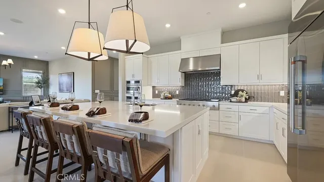 a kitchen with stainless steel appliances granite countertop a sink a stove a refrigerator cabinets and chairs