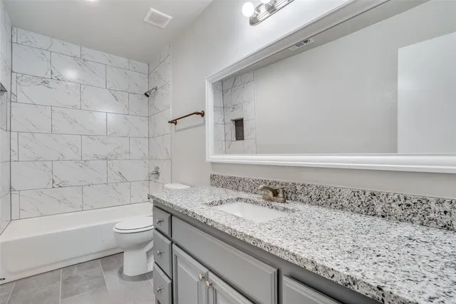 a bathroom with a granite countertop sink a toilet and bathtub
