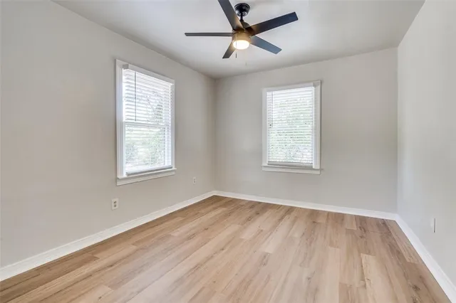 a view of empty room with wooden floor and fan