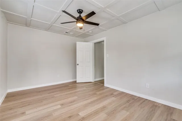an empty room with wooden floor and ceiling fan