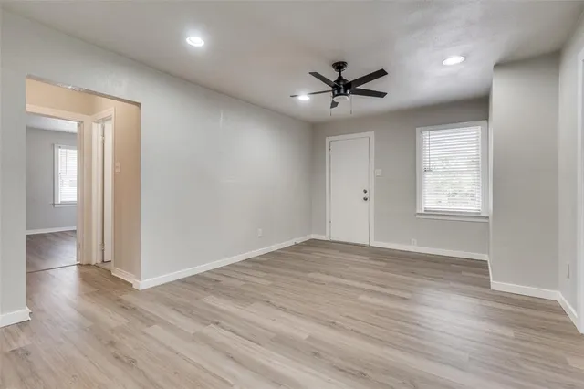a view of an empty room with wooden floor and a window