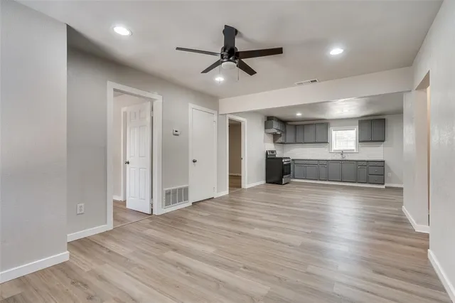 a view of kitchen and empty room with wooden floor