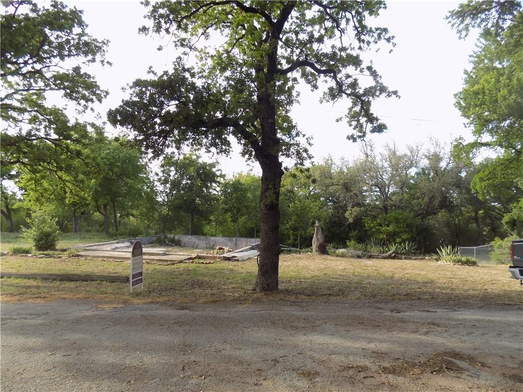a view of dirt field with trees around