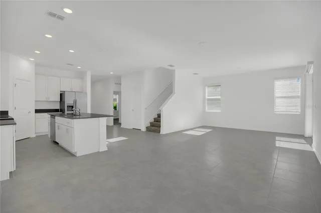 a large kitchen with stainless steel appliances granite countertop a refrigerator a sink a stove a microwave and white cabinets