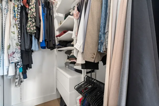 a view of walk in closet with clothes and shoes