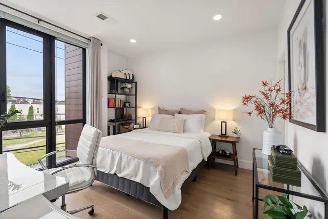 a bedroom with a bed table flowerpot and a window