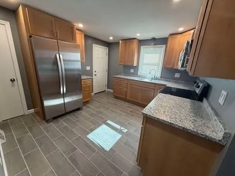 a kitchen with stainless steel appliances granite countertop a sink and a refrigerator