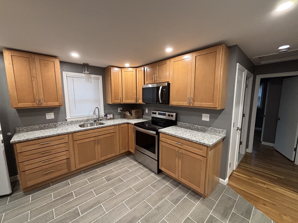 108 Reed Street, Unit R Randolph, MA 02368 - Photo 4 of 21 a kitchen with stainless steel appliances granite countertop a stove a sink and a microwave