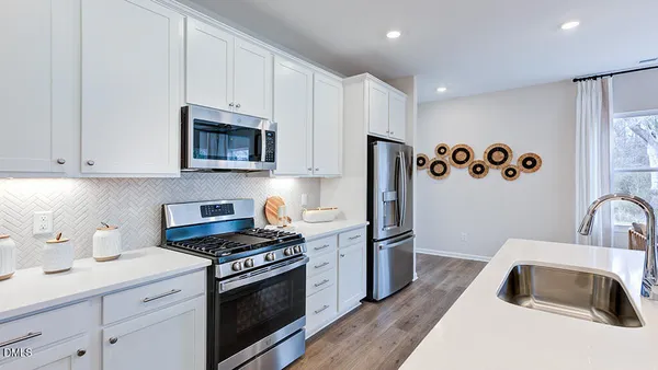 a spacious bedroom with a bed a dresser and a chandelier