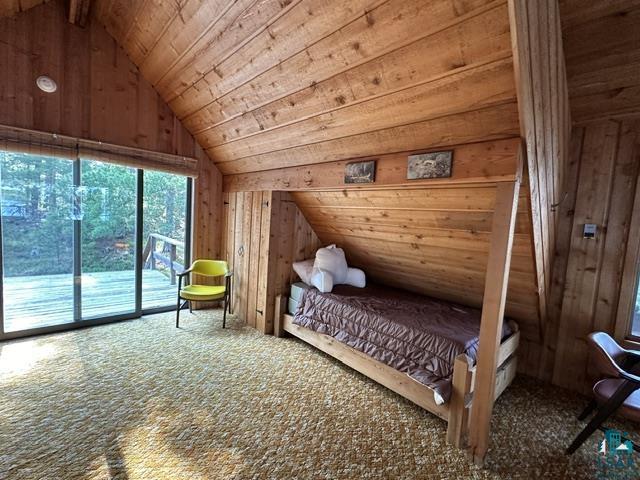 2763 Van Vac Road Ely, MN 55731 - Photo 17 of 37 Sliding glass doors opening to an exterior deck, vaulted wood-paneled ceiling, wood-paneled walls, and wall-to-wall carpeting