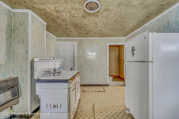 a view of a kitchen with refrigerator and wooden floor