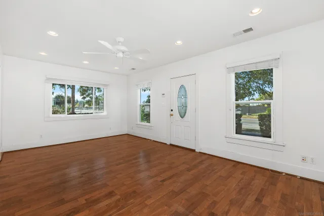an empty room with wooden floor and windows
