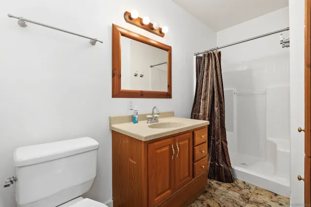 a bathroom with a granite countertop sink toilet and shower