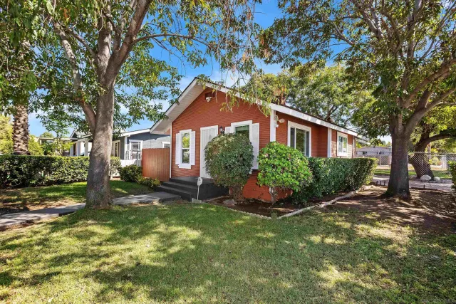 a front view of a house with a yard and tree