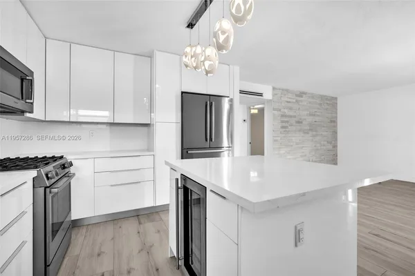 a kitchen with stainless steel appliances granite countertop a sink dishwasher a stove and a refrigerator with wooden floor