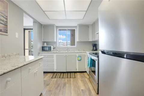 a kitchen with a sink a refrigerator a window and cabinets