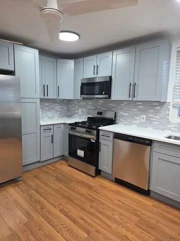 a large kitchen with a large window a sink and stainless steel appliances