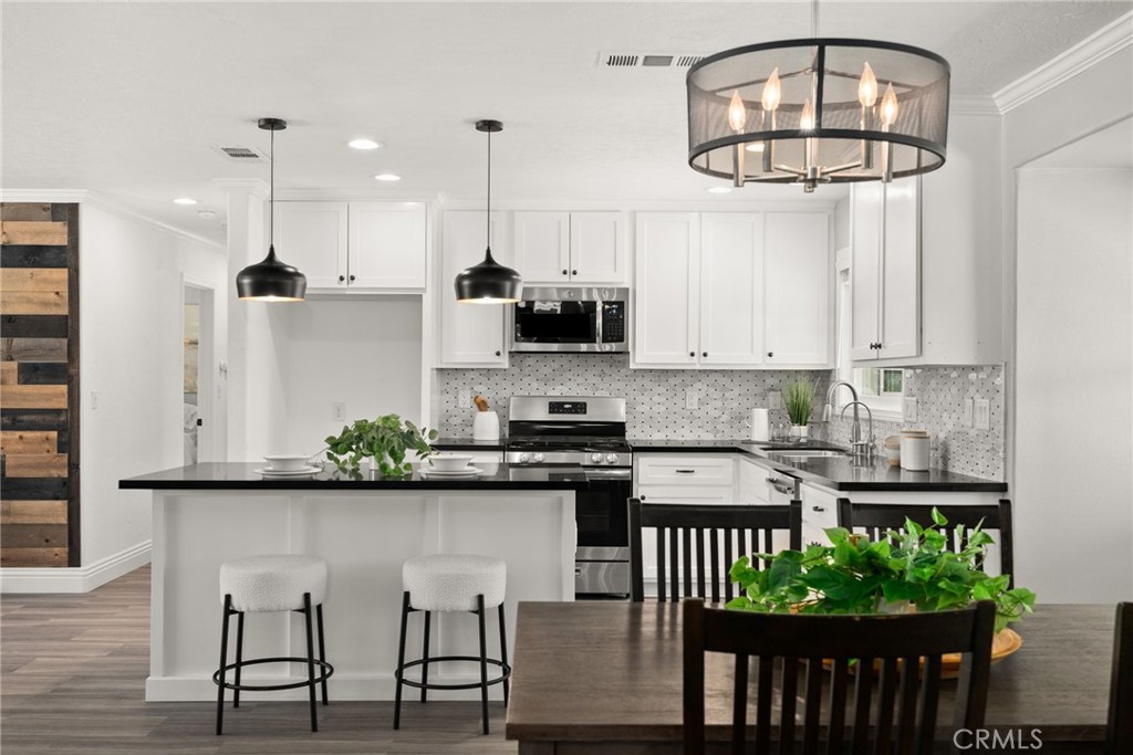 27177 El Rancho Road Menifee, CA 92586 - Photo 1 of 1 a kitchen with stainless steel appliances granite countertop a stove a refrigerator and a dining table with wooden floor