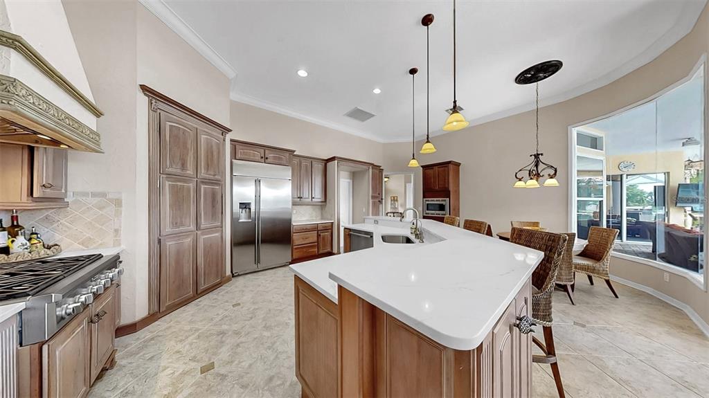 914 Capriccio Lane Apollo Beach, FL 33572 - Photo 28 of 75 a kitchen with stainless steel appliances kitchen island granite countertop a refrigerator a stove a sink dishwasher with a dining table and chairs