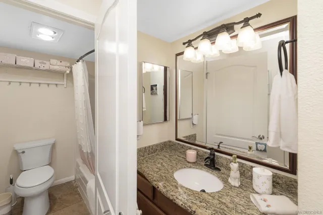 a bathroom with a granite countertop sink toilet and shower