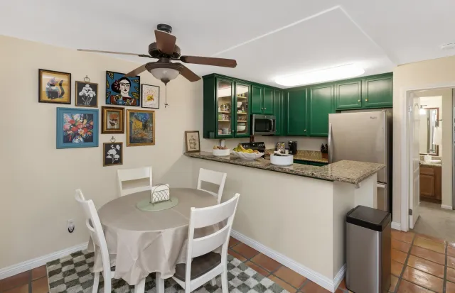 a kitchen with stainless steel appliances kitchen island granite countertop a table chairs and a refrigerator