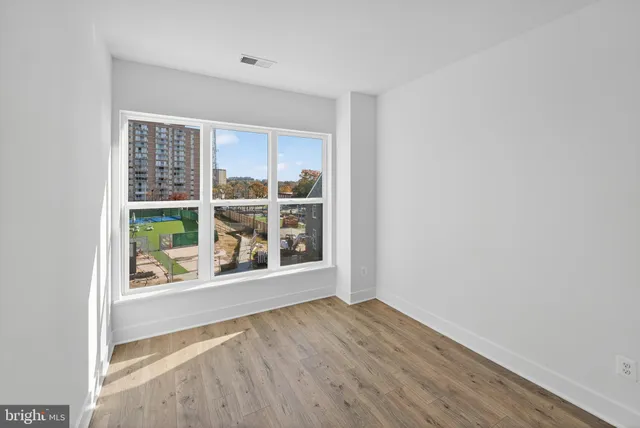 a view of an empty room with wooden floor and a window
