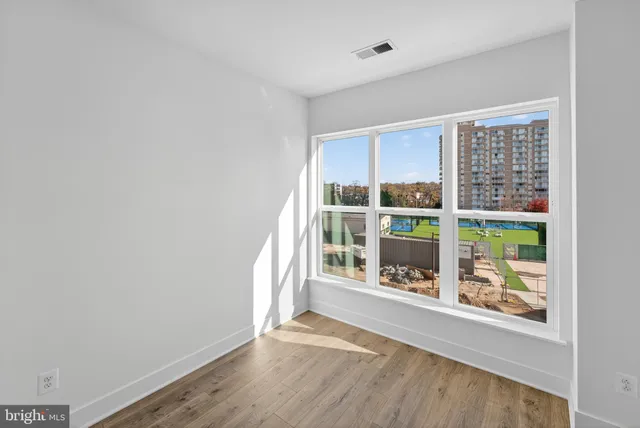 an empty room with wooden floor and windows