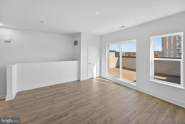 a view of an empty room with a window and wooden floor