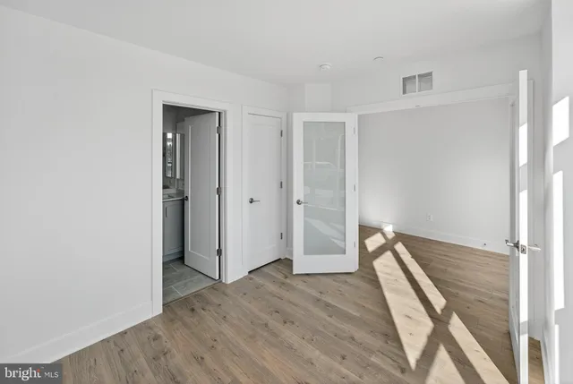 an empty room with wooden floor and a ceiling fan