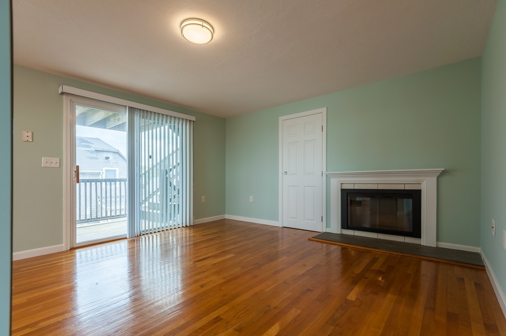 149 Jericho Road, Unit B Scituate, MA 02066 - Photo 13 of 22 an empty room with wooden floor fireplace and windows