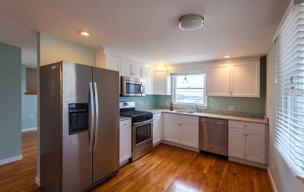 149 Jericho Road, Unit B Scituate, MA 02066 - Photo 5 of 22 a kitchen with stainless steel appliances granite countertop a refrigerator a sink dishwasher a stove with wooden floors and cabinets
