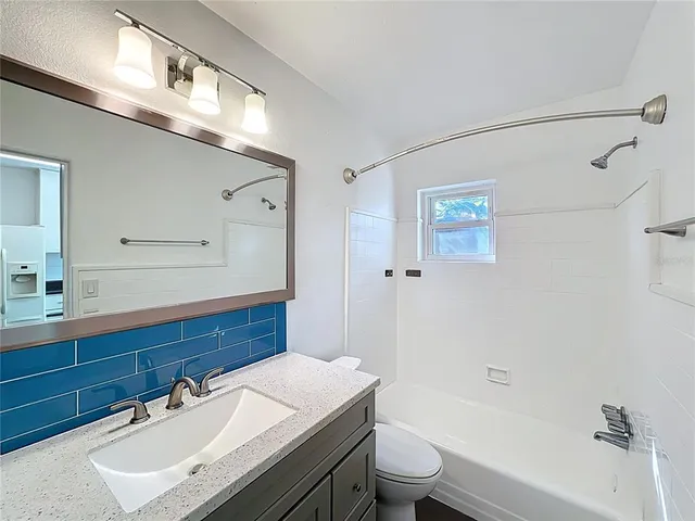a bathroom with a sink vanity granite toilet tub and shower
