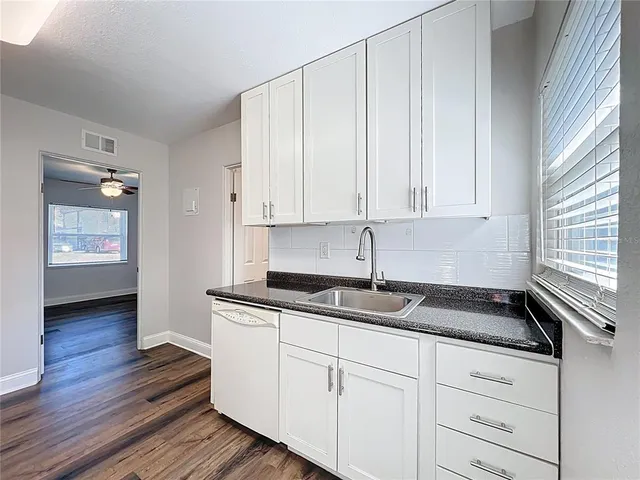a kitchen with granite countertop white cabinets and sink