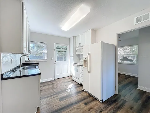 a kitchen with granite countertop a refrigerator and a sink