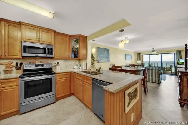 a kitchen with stainless steel appliances granite countertop a stove top oven a sink dishwasher a dining table and chairs with wooden floor