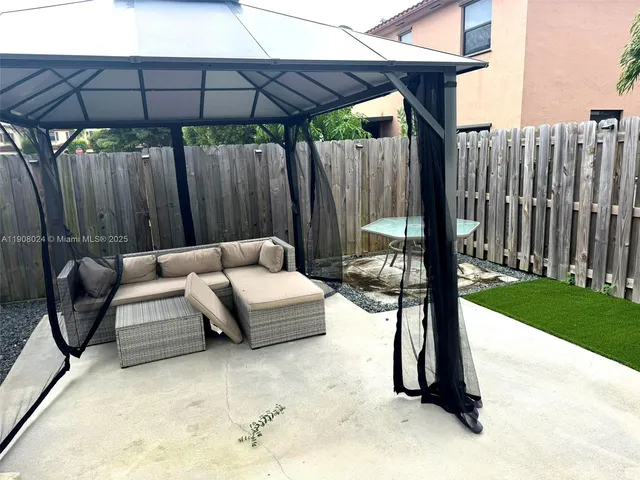a view of patio with a table and chairs under an umbrella with a small yard