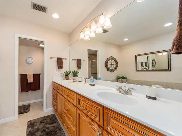 a spacious bathroom with a double vanity sink a mirror and a shower