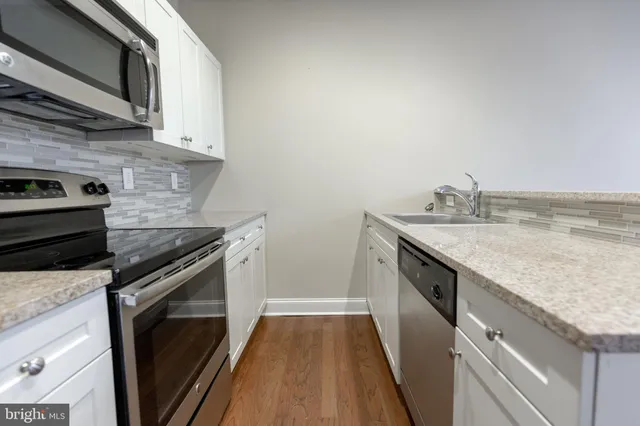 a kitchen with granite countertop a sink stove and cabinets